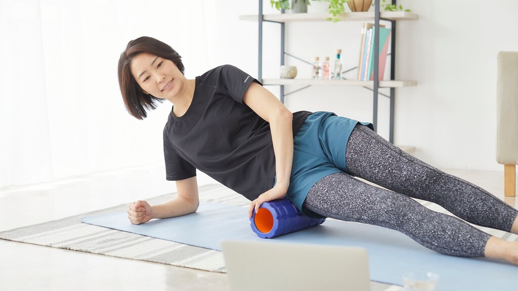 Person using a foam roller on the outer thigh during a home workout.