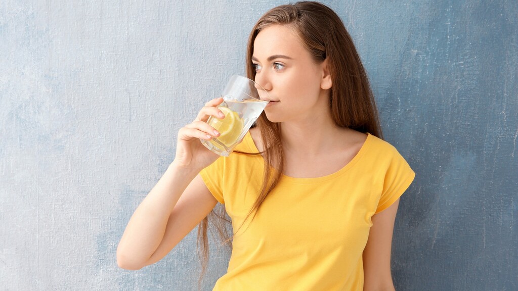 Woman drinking lemon water to support daily hydration and healthy habits.