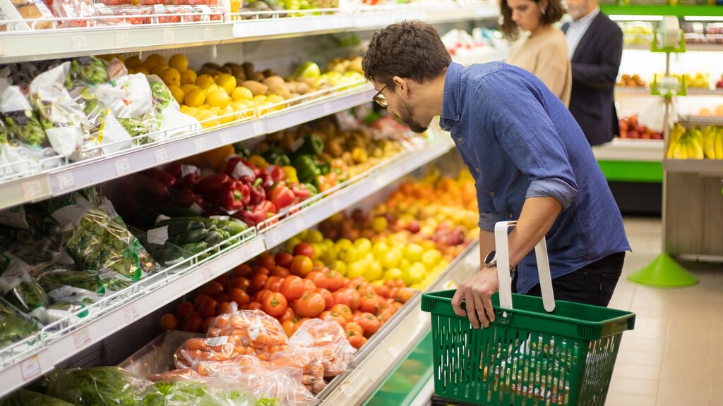 Man shopping for fresh vegetables in the produce section of a grocery store.