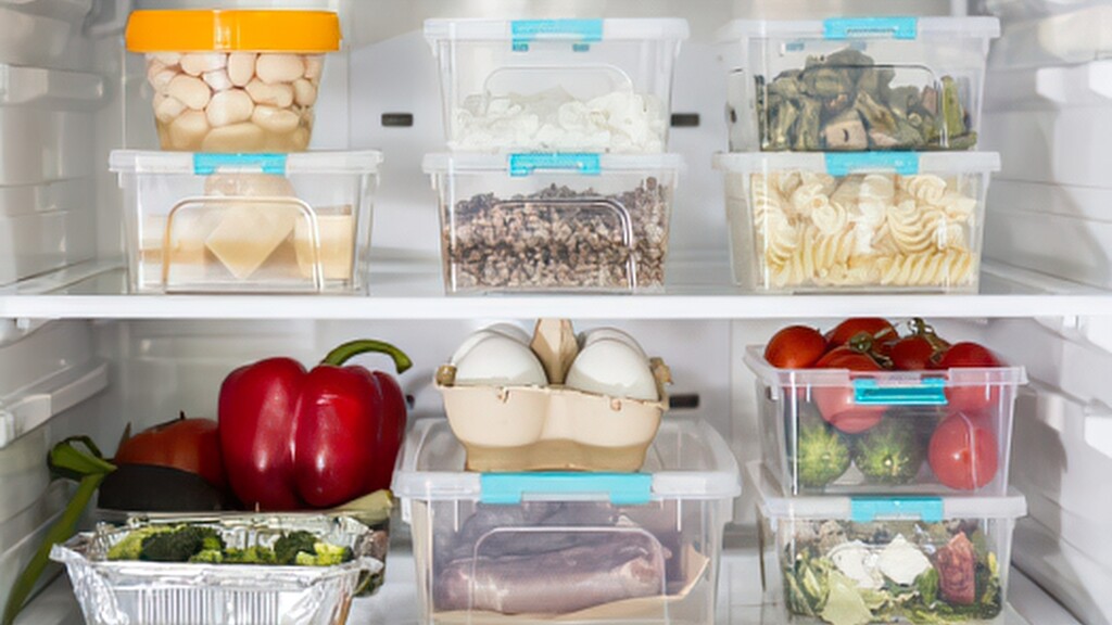 Organized refrigerator with clear containers of vegetables, eggs, cheese, and prepared foods.
