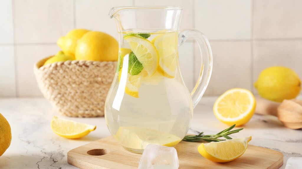 Pitcher of lemon water with mint and ice on a bright kitchen counter.