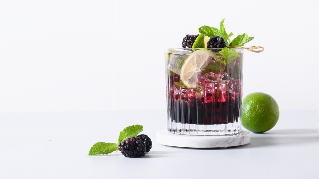 Blackberry mint rum smash with lime, fresh mint, blackberries, and ice in a rocks glass.