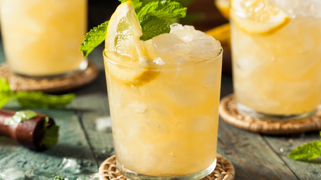 Ginger bourbon smash with lemon, mint, and crushed ice in a rocks glass.