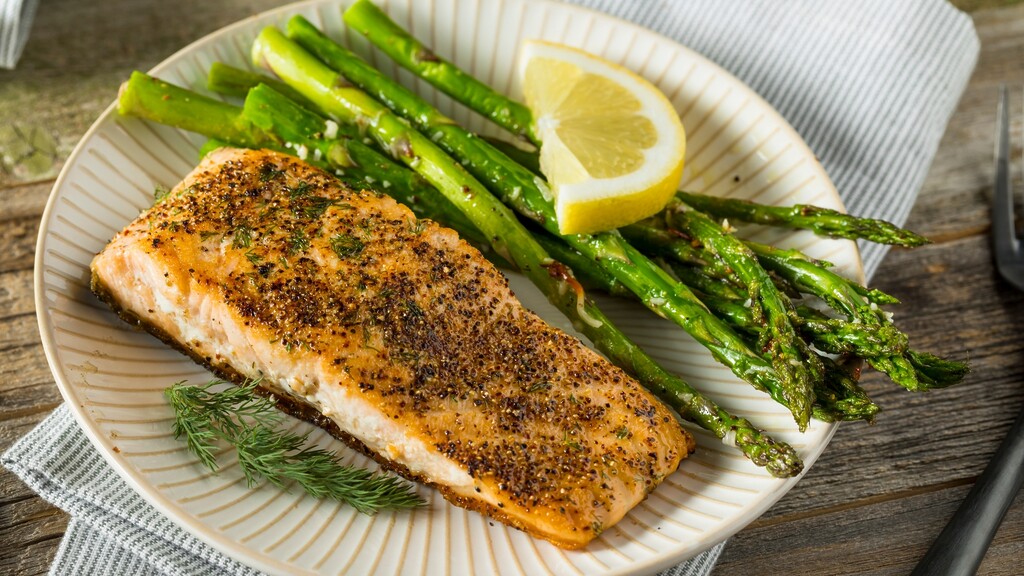 Baked salmon with asparagus and lemon, a meal rich in omega fatty acids for healthy skin.