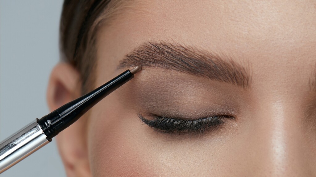 Close-up of a brow pencil filling in a natural eyebrow with soft hair-like strokes.