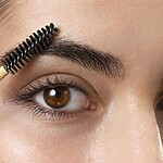 The Complete Routine: 30 Hacks for Perfect Eyebrows Close-up of a woman brushing a full eyebrow upward with a spoolie for a groomed, natural brow shape.