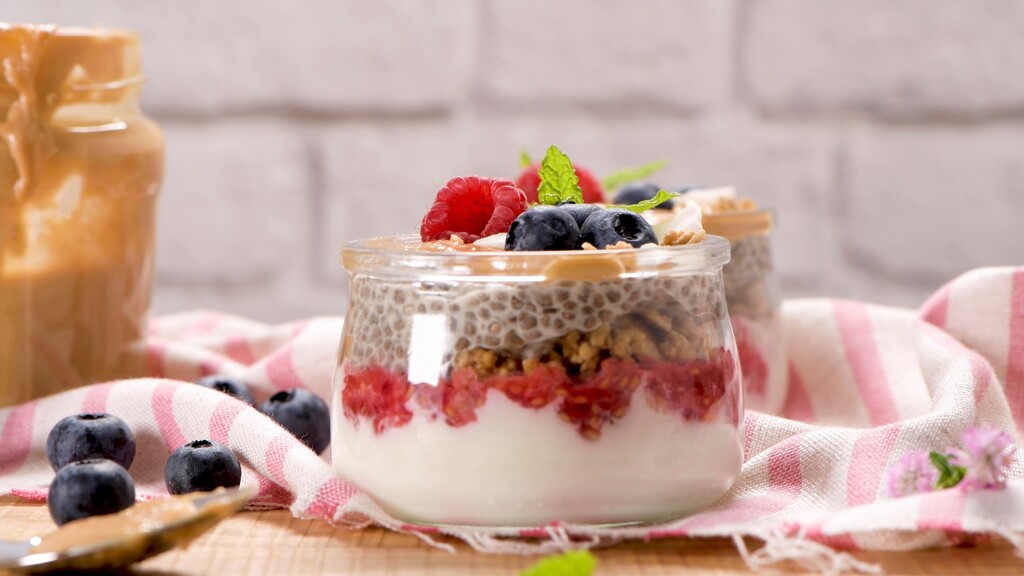 Chia pudding jars layered with yogurt, berries, granola, and peanut butter.
