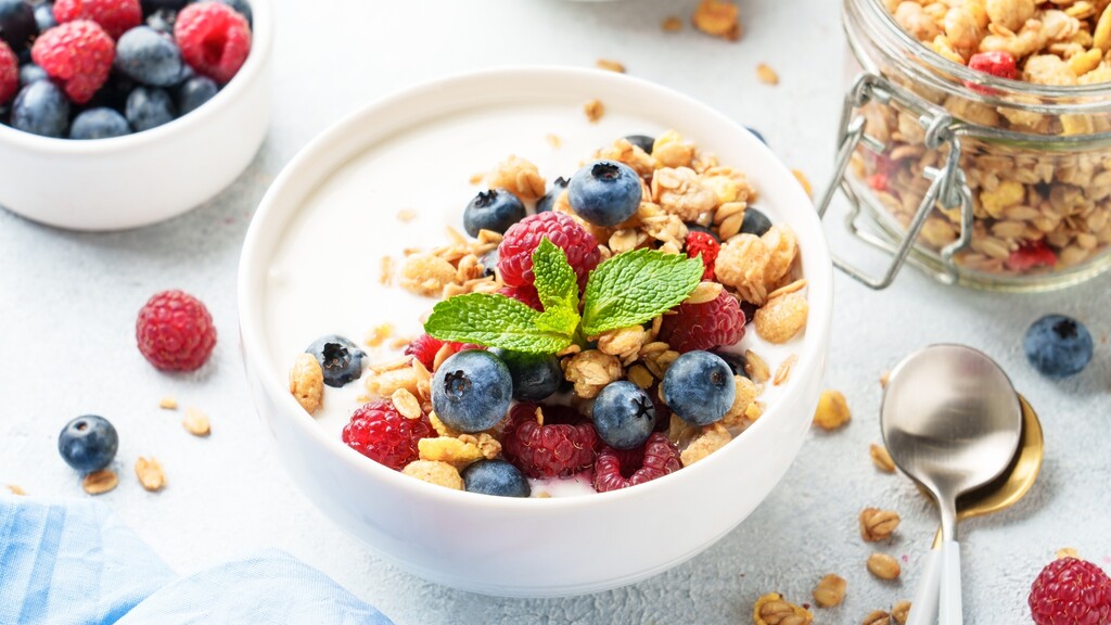 Greek yogurt bowl topped with berries, granola, and fresh mint.