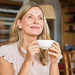 Thoughtful woman holding a cup of tea in a warm home setting, reflecting on early changes in her health.