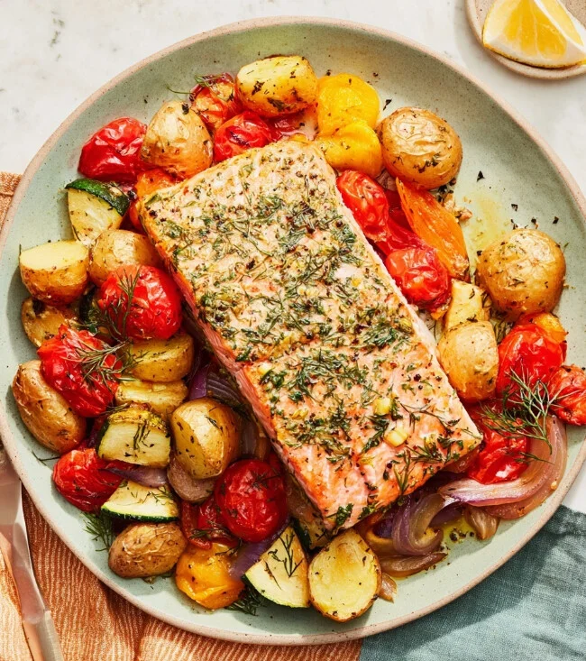 Pan-seared salmon sitting in a rich savory sauce inside a dark skillet