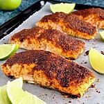 Plated chili lime baked salmon with a dark caramelized spice crust and fresh lime slices