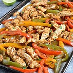 roasted low sodium chicken fajitas on a parchment lined baking sheet with vibrant sliced bell peppers and fresh cilantro
