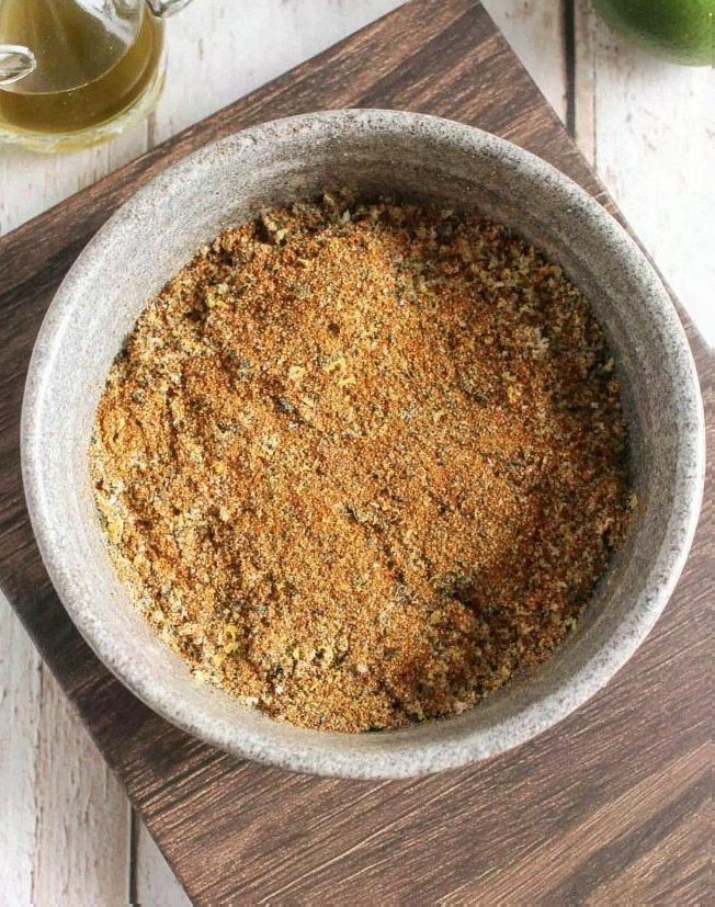 Golden brown chili lime dry spice mix in a stone bowl on a wooden board