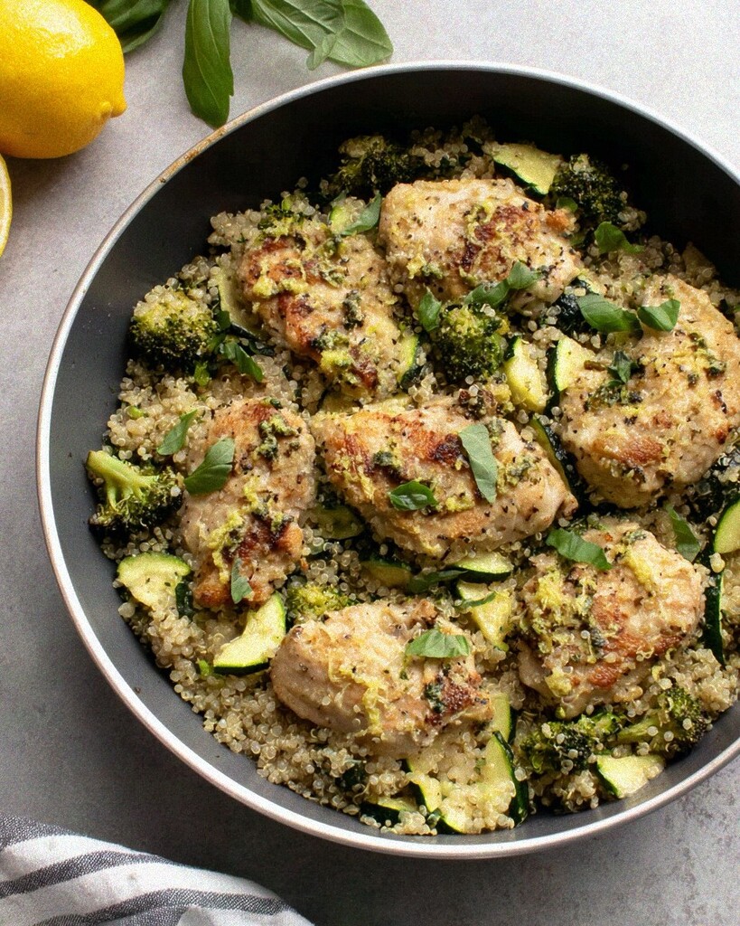 A deep skillet filled with seared chicken breast, fluffy quinoa, bright green broccoli, and zucchini tossed in fresh lemon basil