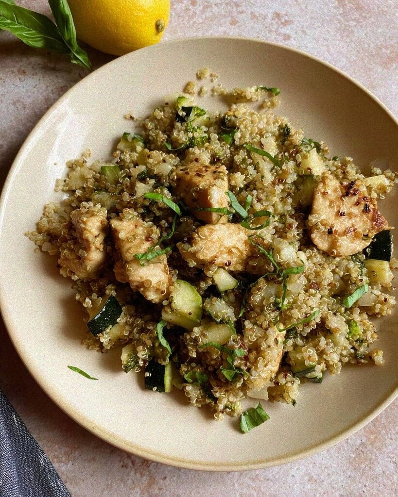 A ceramic bowl serving of lemon basil chicken with fluffy quinoa and crisp steamed vegetables